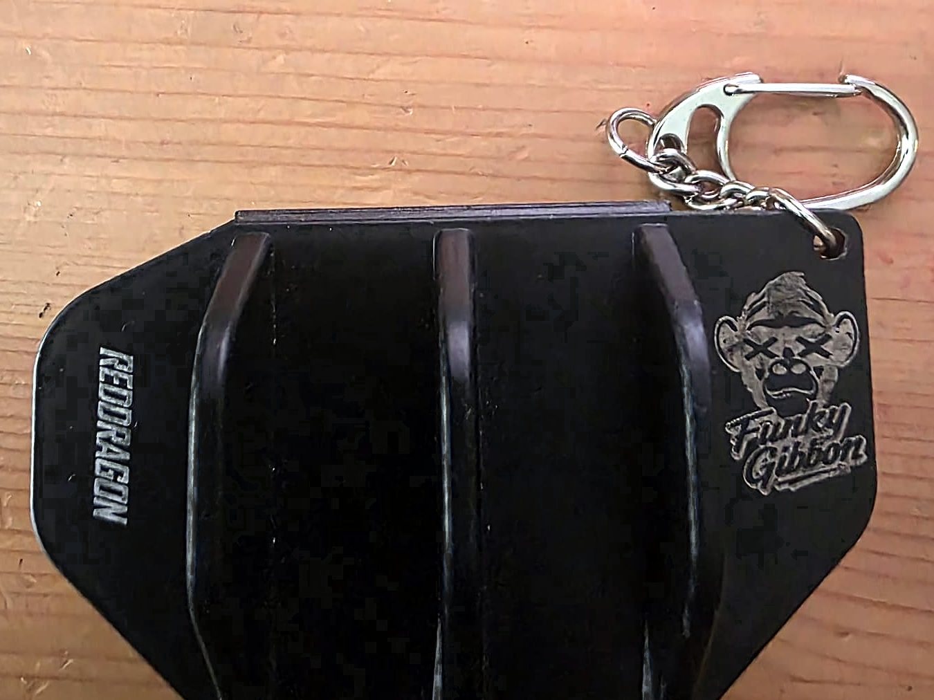 A black dart case engraved with the Funky Gibbon logo, a cartoon ape, on its lid