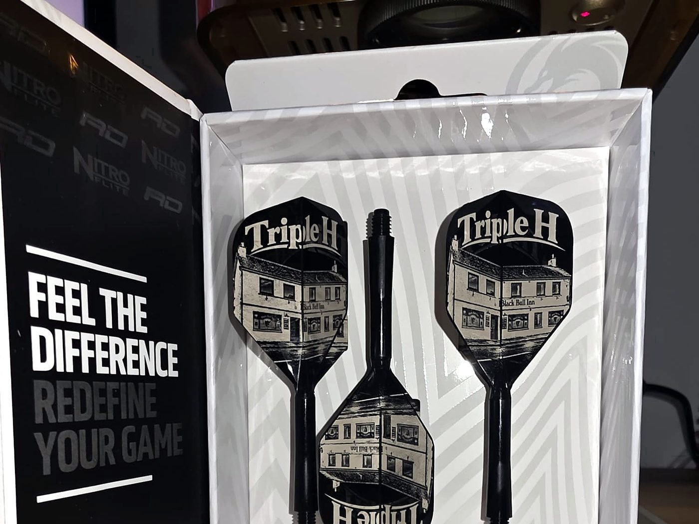 A Triple H pub set of three black flights, engraved with the pub building, in a boxed presentation case