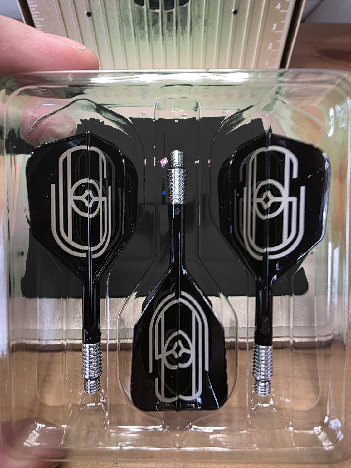 Three black flights engraved with a tall art deco monogram, in their tray