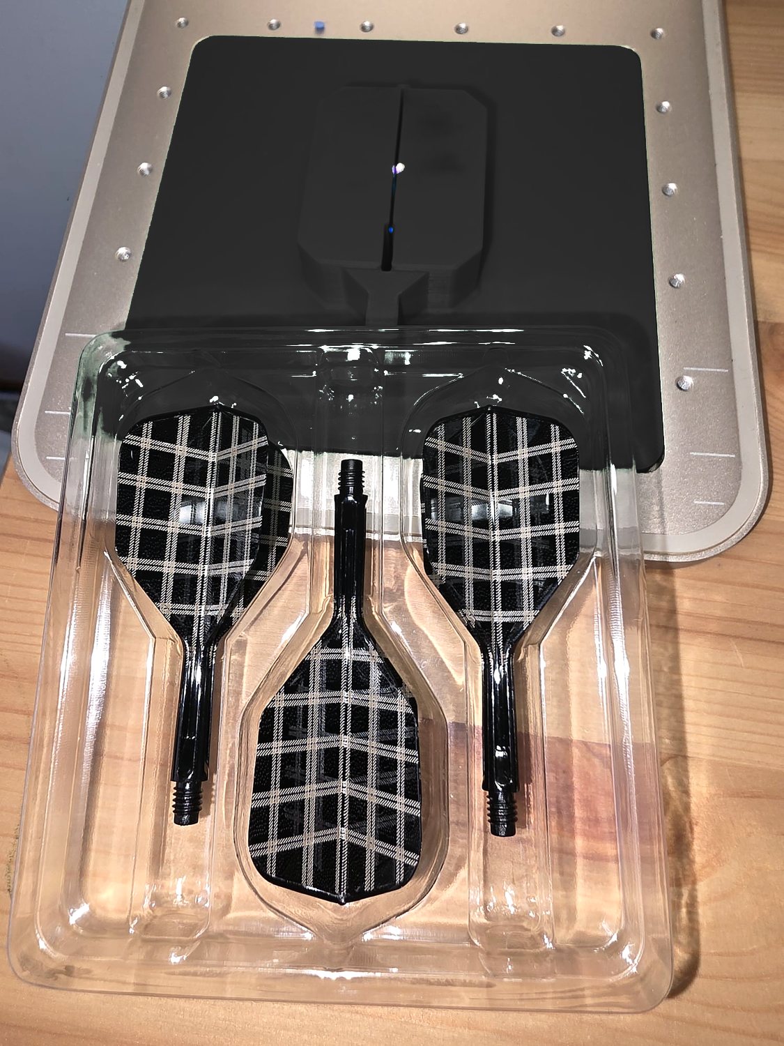 Three black flights engraved in a white tartan check, in their tray