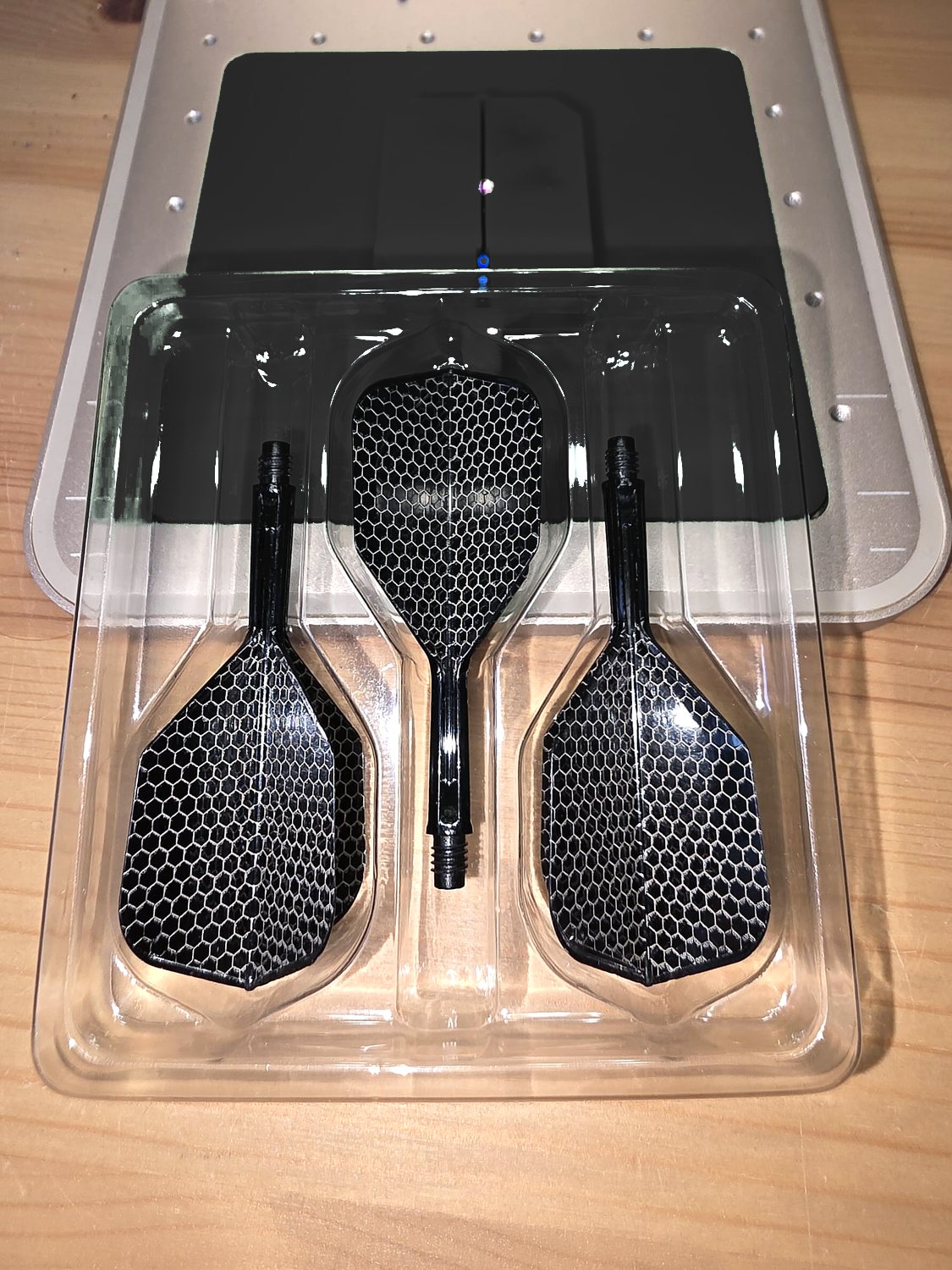 Three black flights engraved in a white honeycomb pattern, in their tray